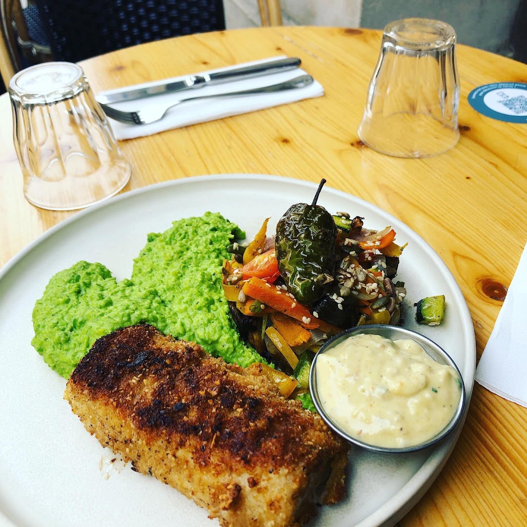 Un poisson pané avec purée de petits pois, légumes et sauce